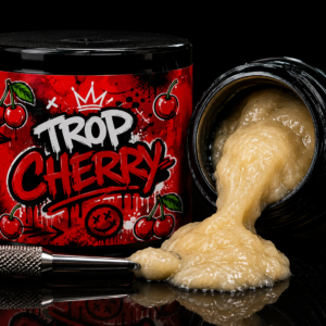 Tropicana Cherry premium cannabis concentrate in sealed black jar with red label showing cherry graphics, tan concentrate visible inside with application brush